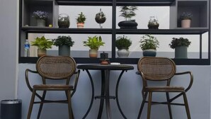Two wicker chairs and a small round table in front of a window with shelves holding potted plants. - GreenTree Inn (Beijing Hospital of Traditional Chinese Medicine, Nanluogu Lane, Houhai) (Beijing)
