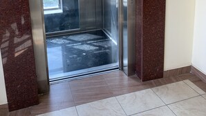 An elevator with a warning sign, a number 7 on the wall, and a tiled floor. - The Beautiful 3Br All En-suite Apt (Mombasa)