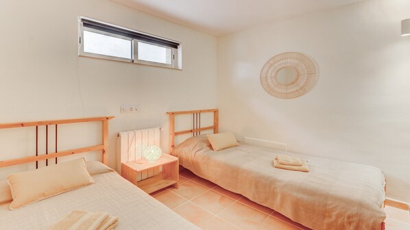 Une chambre avec deux lits, une table de chevet avec une lampe, un miroir fixé au mur et une fenêtre.