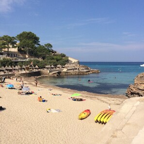 Une plage avec des parasols, des gens et une côte rocheuse.