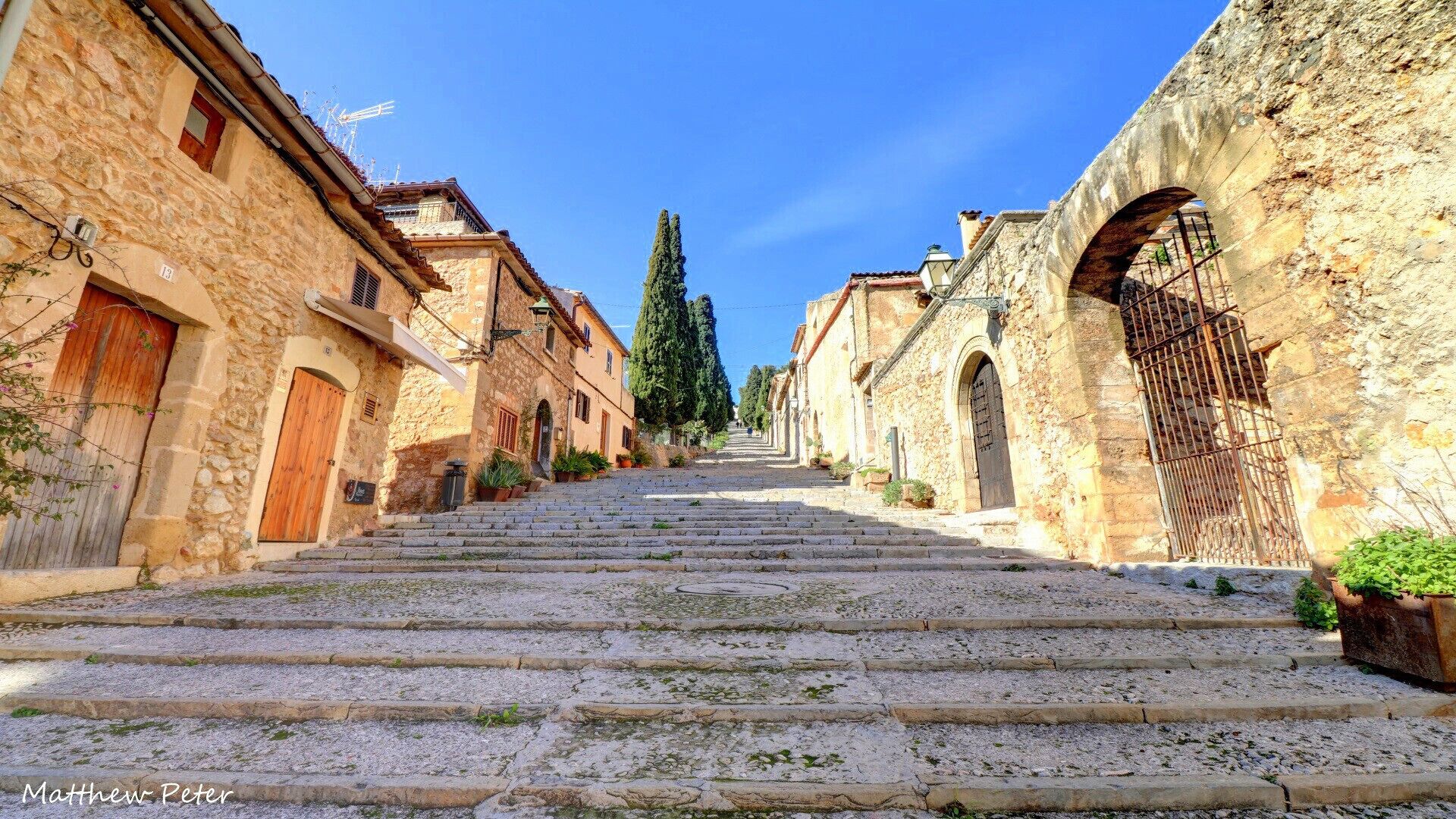 A stone staircase leading up to a town square with old buildings on either side.