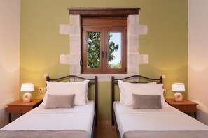 A hotel room with two beds, a window with a view of trees, and bedside lamps.