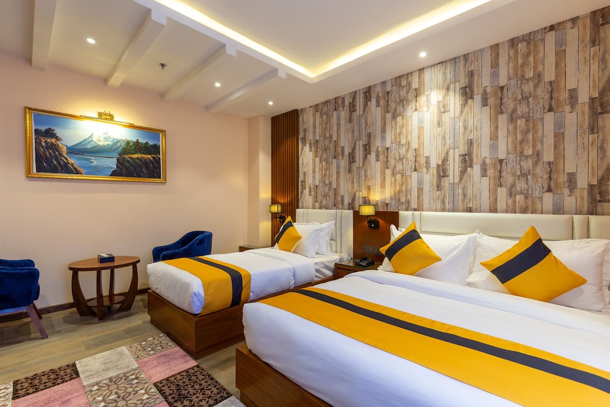 A hotel room with two beds, a painting on the wall, a wooden headboard, and a patterned rug.