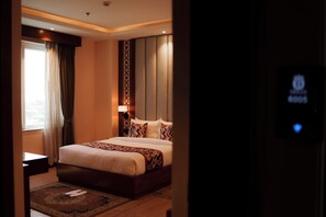A hotel room with a bed, a nightstand, a lamp, and a view of the outside. - Dream International Hotel (Butwal)