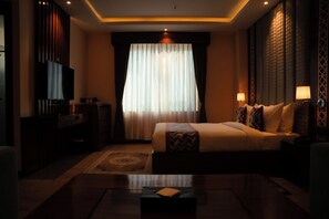 Una habitación de hotel con cama, lámparas de noche, televisión y escritorio.