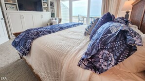 Ein Schlafzimmer mit einem großen Bett, einem Fernseher, einem Sessel und einem Balkon mit Blick.