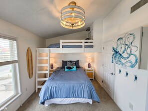 Un dormitorio con literas, una tabla de surf, una lámpara en el techo y un cuadro de un pulpo en la pared.
