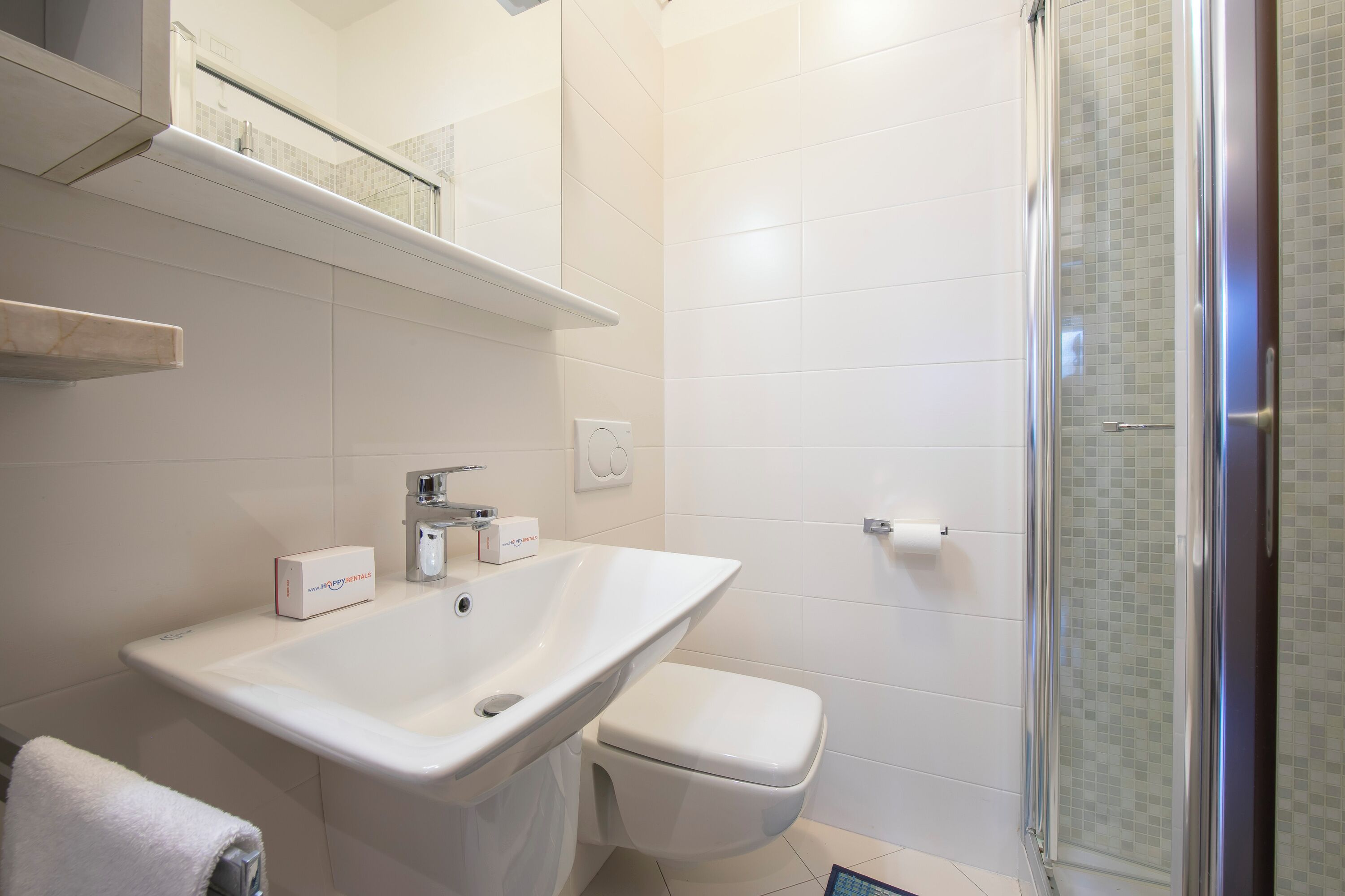 Un baño con lavamanos blanco, inodoro y cabina de ducha de vidrio.