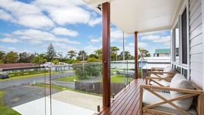 Un balcon doté d’une terrasse en bois, de rampes en verre et d’un espace salon extérieur.