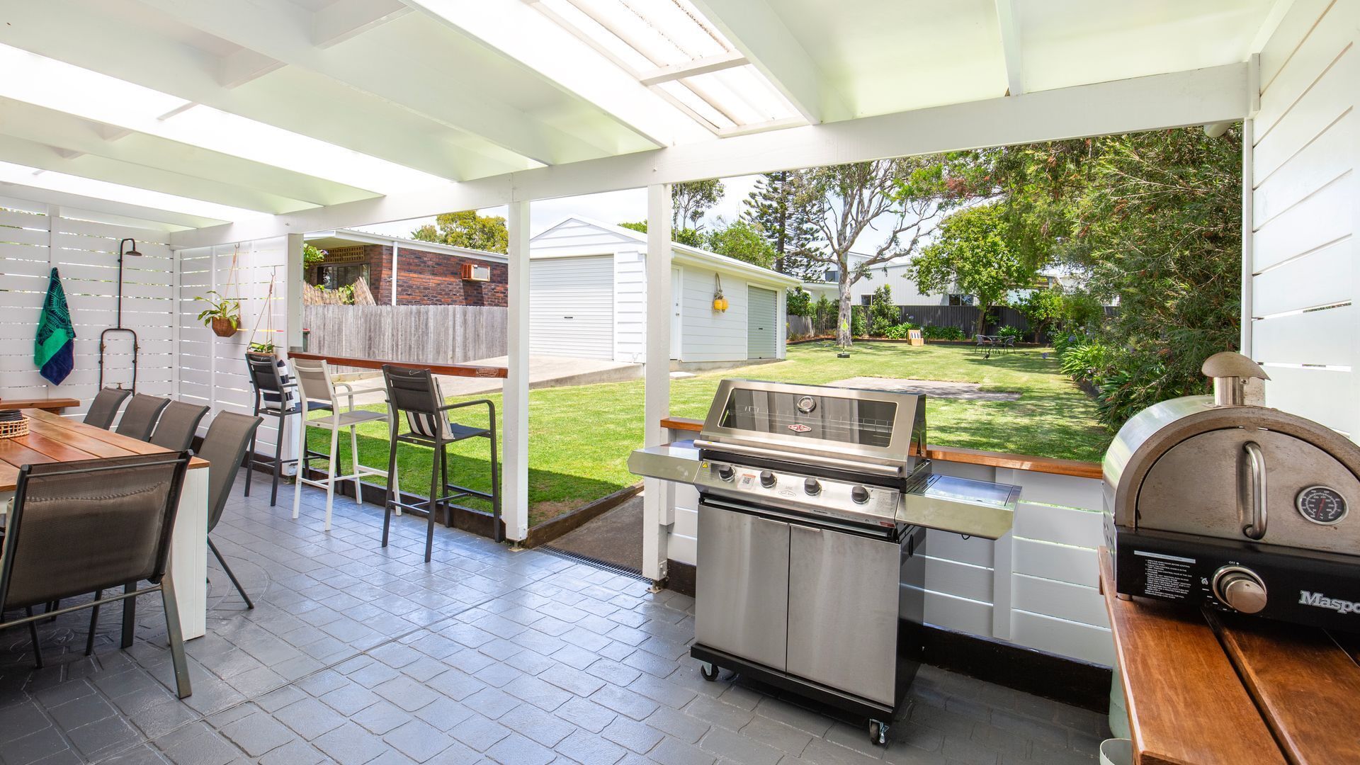 Eine Terrasse mit Grill, Stühlen und einem Tisch.