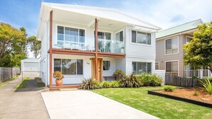 Un immeuble résidentiel de deux étages, doté d’un balcon à l’étage supérieur, d’un garage et d’une pelouse bien entretenue.