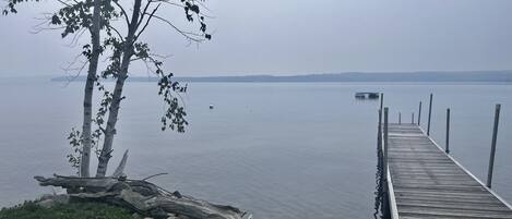 A wooden dock extending into calm water, surrounded by rocks and greenery.