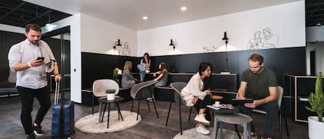 A modern lounge area with seating arrangements, a coffee table, and a potted plant.