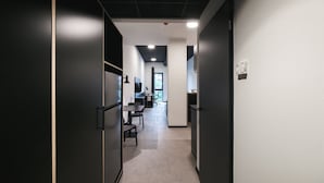 A modern office space with a long hallway leading to a desk area with a computer and chair. - MoLiving - Design Hotel & Apartments Düsseldorf-Neuss (Neuss)