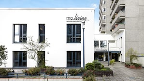 A modern serviced apartment building with a white facade, large windows, and a sign reading "mo.living". - MoLiving - Design Hotel & Apartments Düsseldorf-Neuss (Neuss)