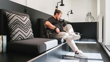 A person sitting on a black sofa with a chevron-patterned pillow, holding a cat.