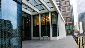 A modern building with large glass windows and a paved walkway. - The Wardian (London)