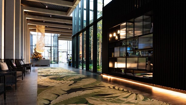A lobby with a large floral carpet, seating area, and a reception desk with glass display cases. - The Wardian (London)