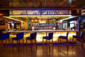 A bar area with a 'SABIO' sign, wooden bar counter, and blue bar stools. - Treebo New Rockwell Vivek Vihar (Jaipur)