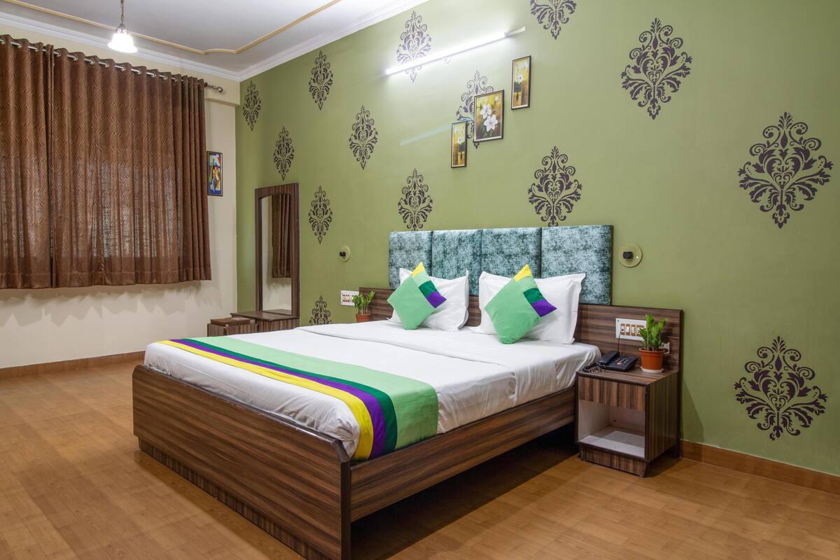Een keurig opgemaakt slaapkamer met een houten bed, groene wanden en decoratieve muurmotieven.