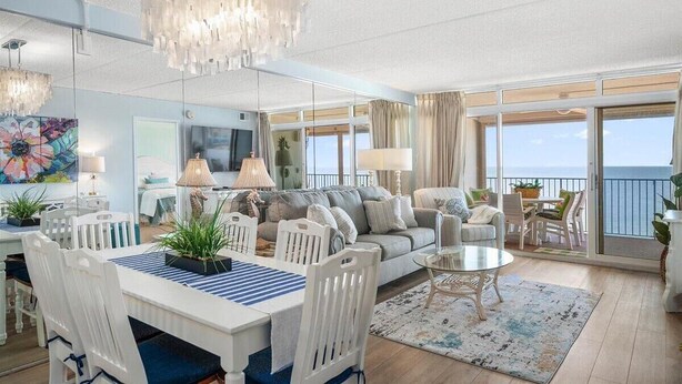 Un vaste espace de vie comprenant un coin repas, un canapé et un balcon avec vue.