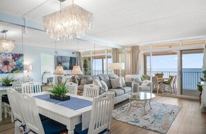 Een ruime woonkamer met een eethoek, een bank en een balkon met uitzicht.