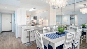 Une cuisine moderne avec des meubles blancs, un îlot central et des tabourets de bar.