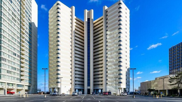 En modern byggnad med en central innergård och en parkeringsplats.