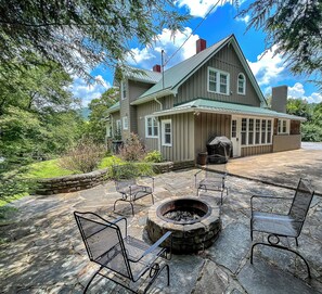 Une maison dotée d’un patio en pierre, d’un espace salon extérieur et d’un foyer.