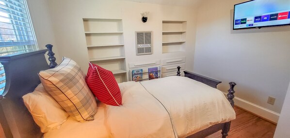 Une chambre à coucher avec un lit, un téléviseur fixé au mur et des étagères intégrées.