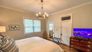 Un dormitorio con cama, candelabro, televisor y cómoda.