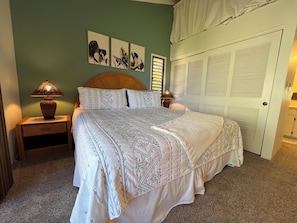 A bedroom with a bed, nightstands, a lamp, a door, and wall art. - Wailea Ekolu #906 Great Location, Panoramic Ocean View, Private, Full A/C (Wailea)
