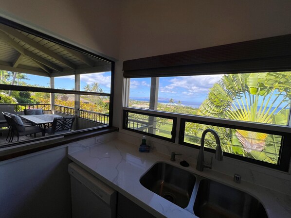 A kitchen with a view of a balcony and outdoor scenery.