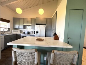 A modern kitchen with grey cabinets, a white island, and a built-in microwave.