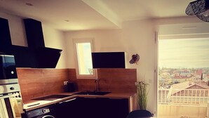 Une cuisine compacte comprenant un évier, un lave-linge et un coin repas avec une table ronde et des chaises.