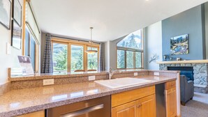 Eine moderne Küche mit Granit Arbeitsplatten, Edelstahlgeräten und großen Fenstern mit Blick ins Freie.