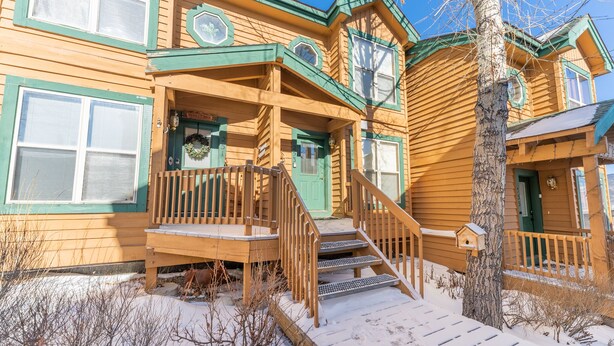 Une maison en bois avec un porche, des marches et un sol recouvert de neige.