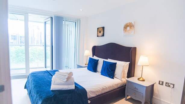Une chambre d’hôtel avec un grand lit, une table de chevet avec une lampe et une vue sur l’extérieur par une fenêtre.