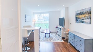 Un salon moderne avec un canapé, une table à manger, un téléviseur et une grande fenêtre.