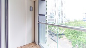 Un balcon doté d’une balustrade en verre donnant sur un paysage urbain.