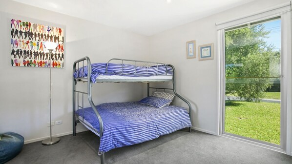 Une chambre avec des lits superposés donnant sur un espace verdoyant grâce à une grande fenêtre.