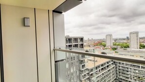 A balcony with a view of modern buildings and a cloudy sky.