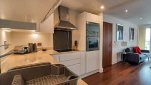 A modern kitchen with a built-in oven and a dining area with a sofa and a small table.