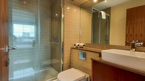 A modern bathroom with a glass shower enclosure, a white sink, and a large mirror.