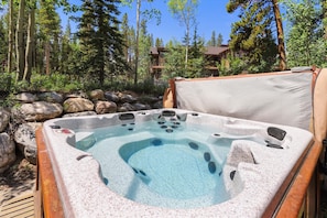 Relax in a serene hot tub surrounded by trees and a wooden deck.