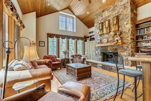 Relax in this elegantly furnished living room with a stone fireplace, comfortable seating area, and large windows.