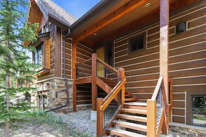 Stunning log cabin with a spacious staircase and large window, set amidst a serene evergreen backdrop.