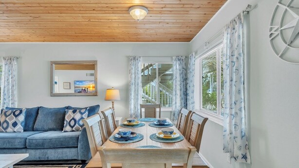 Un comedor con una mesa de madera, cojines estampados azules y una lámpara.