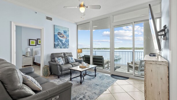 Ein geräumiges Wohnzimmer mit grauem Sofa, einem Couchtisch und einem Balkon mit Meerblick.