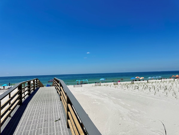 Walk along the beachside path to a serene beach area with shaded relaxation spots and ocean views.